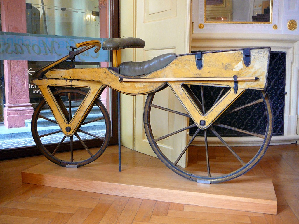 Historische hölzerne Laufmaschine mit Lederpolster und großen Speichenrädern in einem Museum