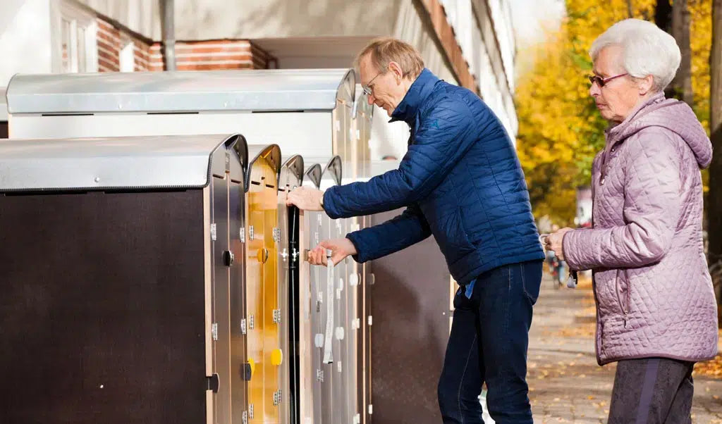Älteres Paar öffnet Briefkästen an einem sonnigen Herbsttag mit gelben Blättern