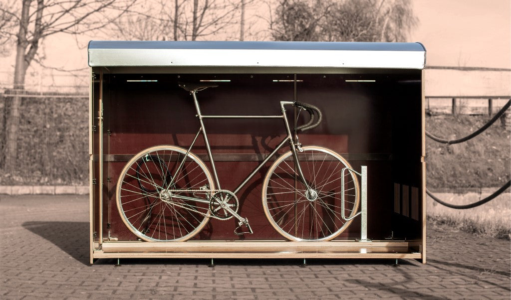 Schwarzes Vintage-Fahrrad steht in moderner Fahrradgarage auf gepflastertem Boden bei Tageslicht