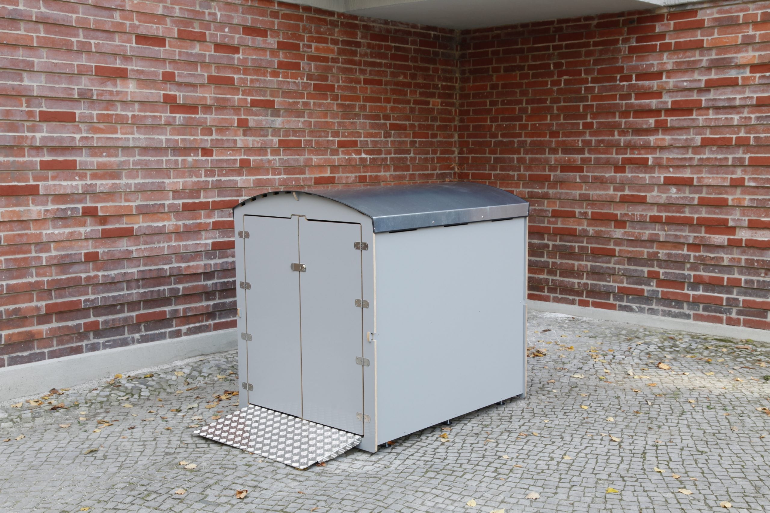 Große Aufbewahrungsbox für Rollatoren mit Rampe, diebstahlsicher, vor Backsteinwand