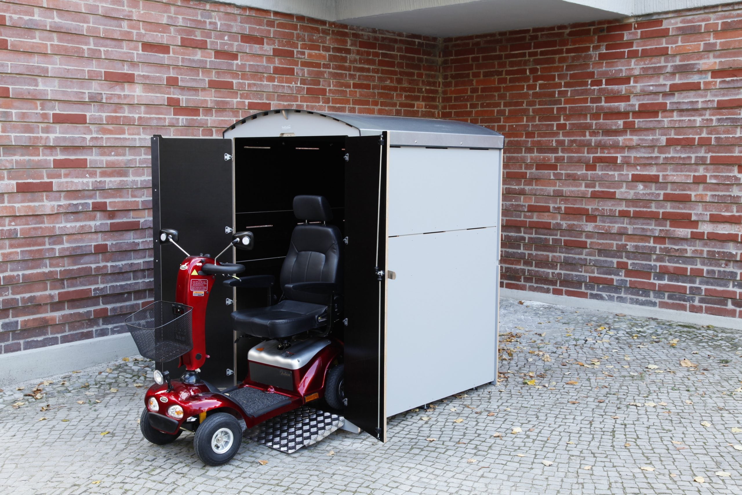 Abschließbare Aufbewahrungsbox für Rollator mit geöffneter Tür und rotem Elektromobil