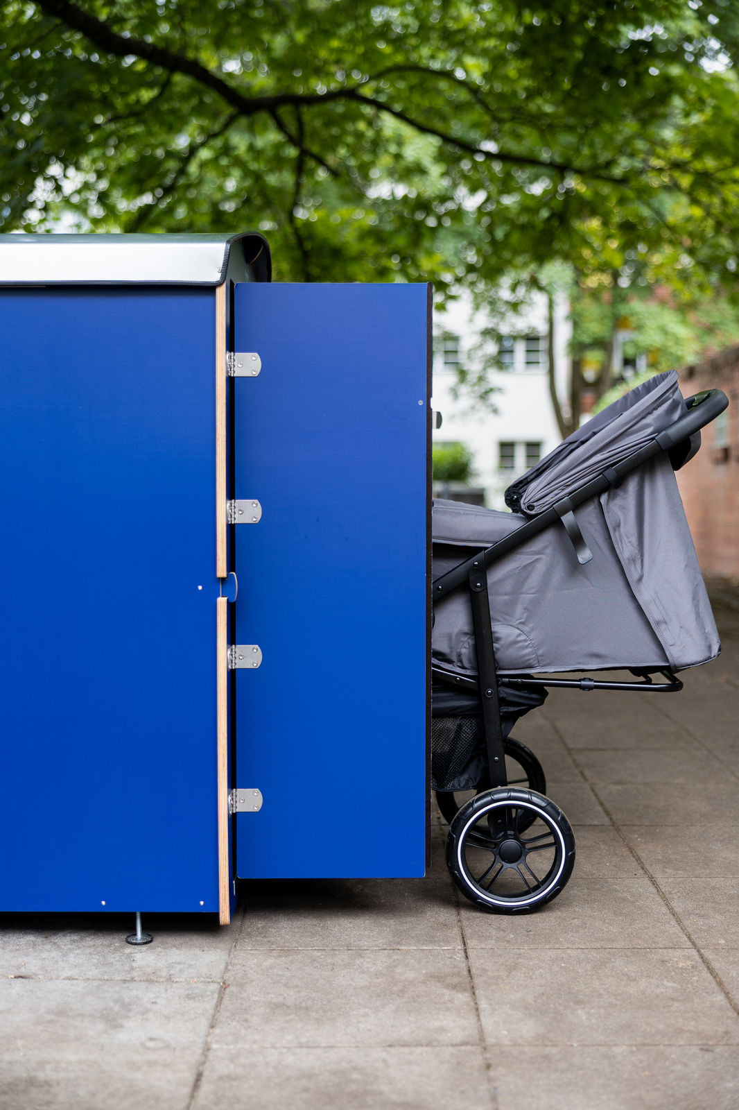 Blaue kiwabo Box seitlich mit Kinderwagen, Hochformat