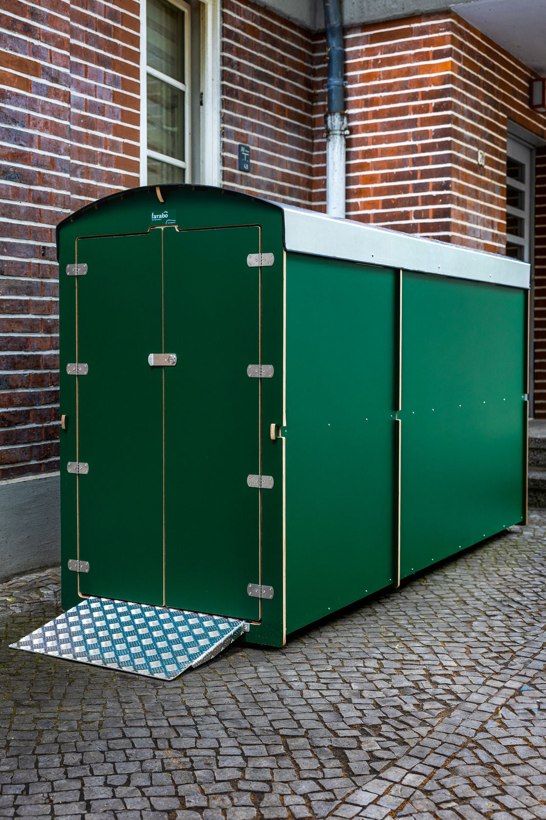 Grüne farabo Box mit Rampe auf Hofpflaster, Hochformat