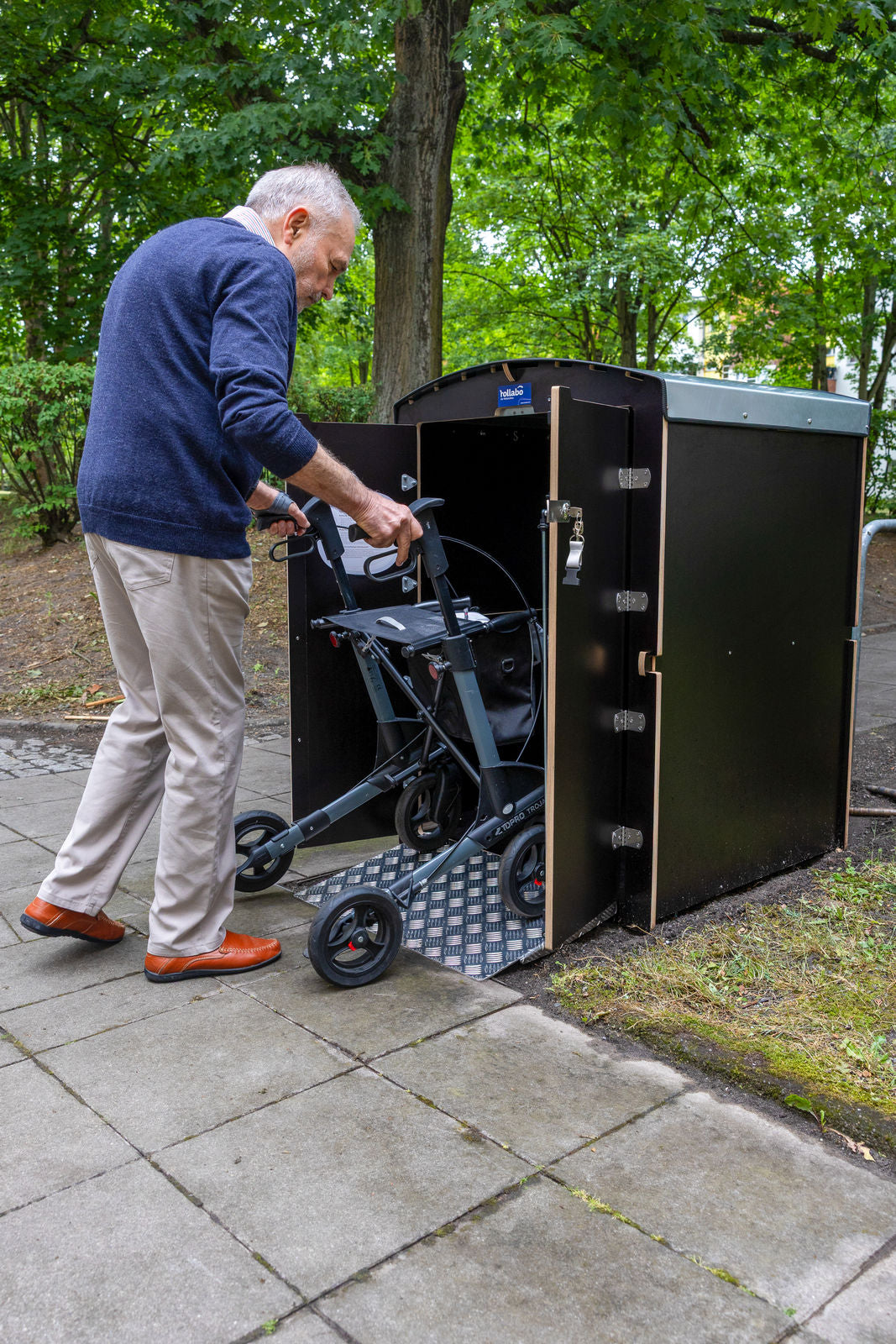 Senior stellt Rollator in eine schwarze rollabo Box, Hochformat