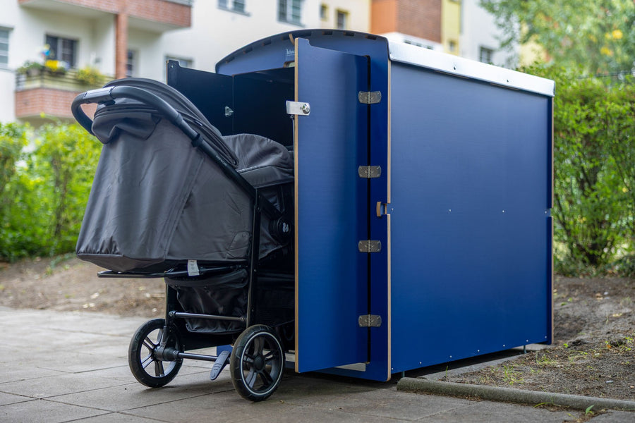 Blaue kiwabo Kinderwagenbox, geöffnet, mit Kinderwagen in einer Grünanlage