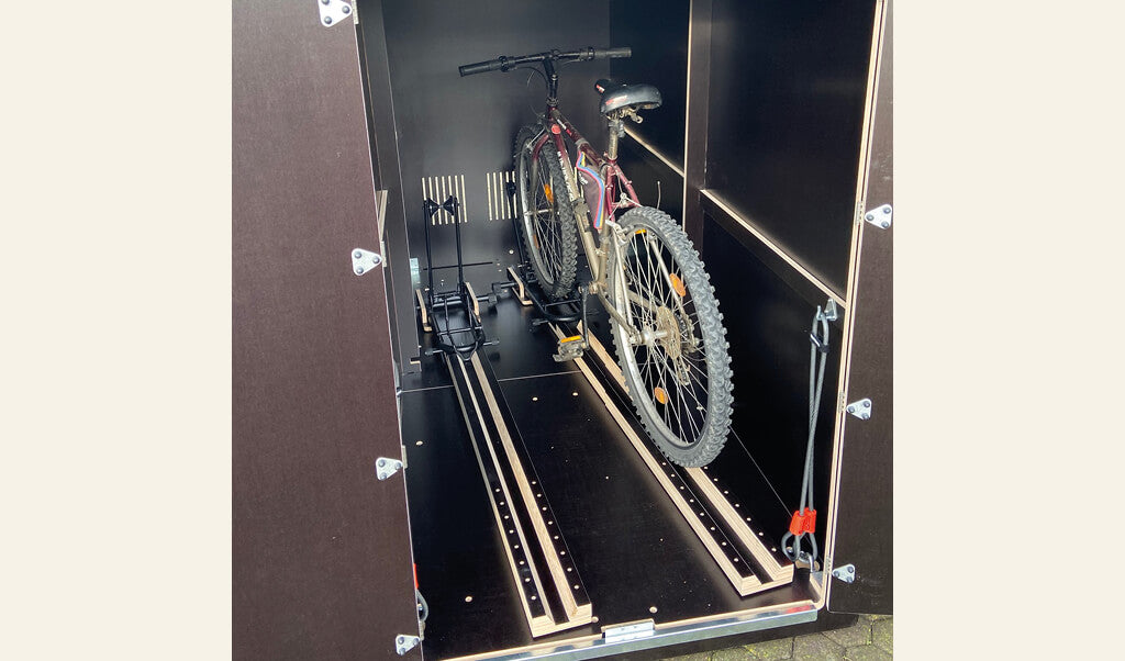 Fahrrad in schwarzer Transportbox mit Einfahrtsschienen und Haltevorrichtungen, Seitenwände mit Metallbeschlägen