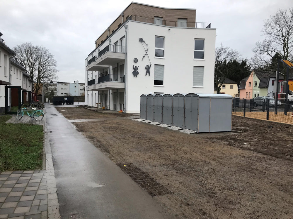 Reihen sichere Aufbewahrungsboxen für Kinderwägen und Fahrräder vor modernem Wohnhaus