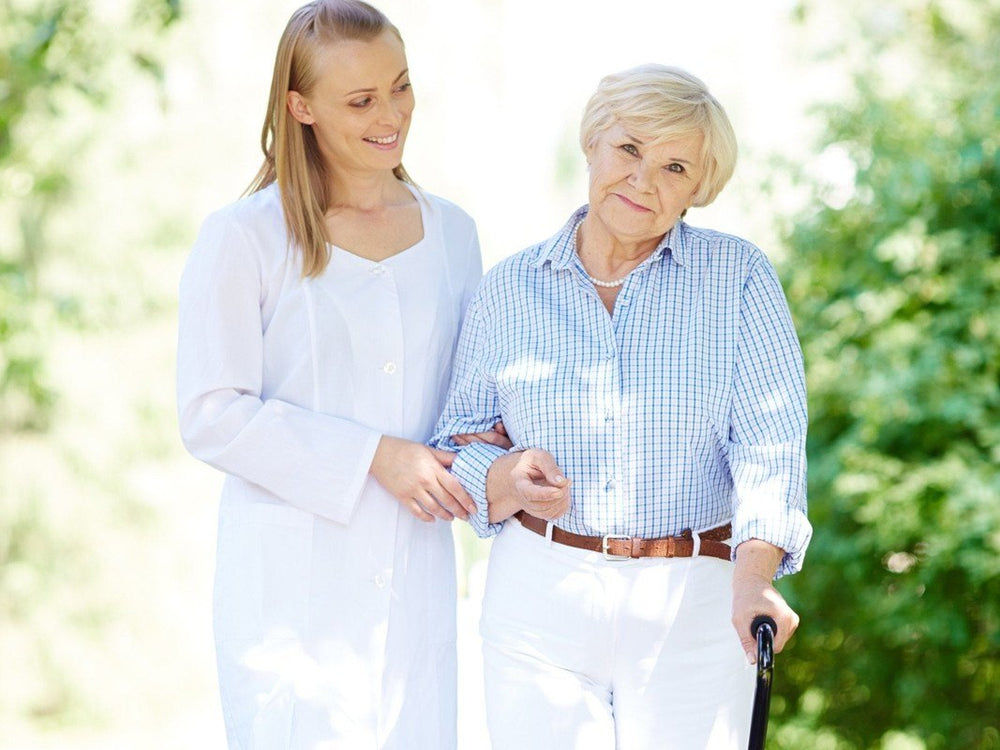 Seniorin mit Rollator und Pflegerin vor der Praxis – Rollatorboxen für Orthopädie und Geriatrie